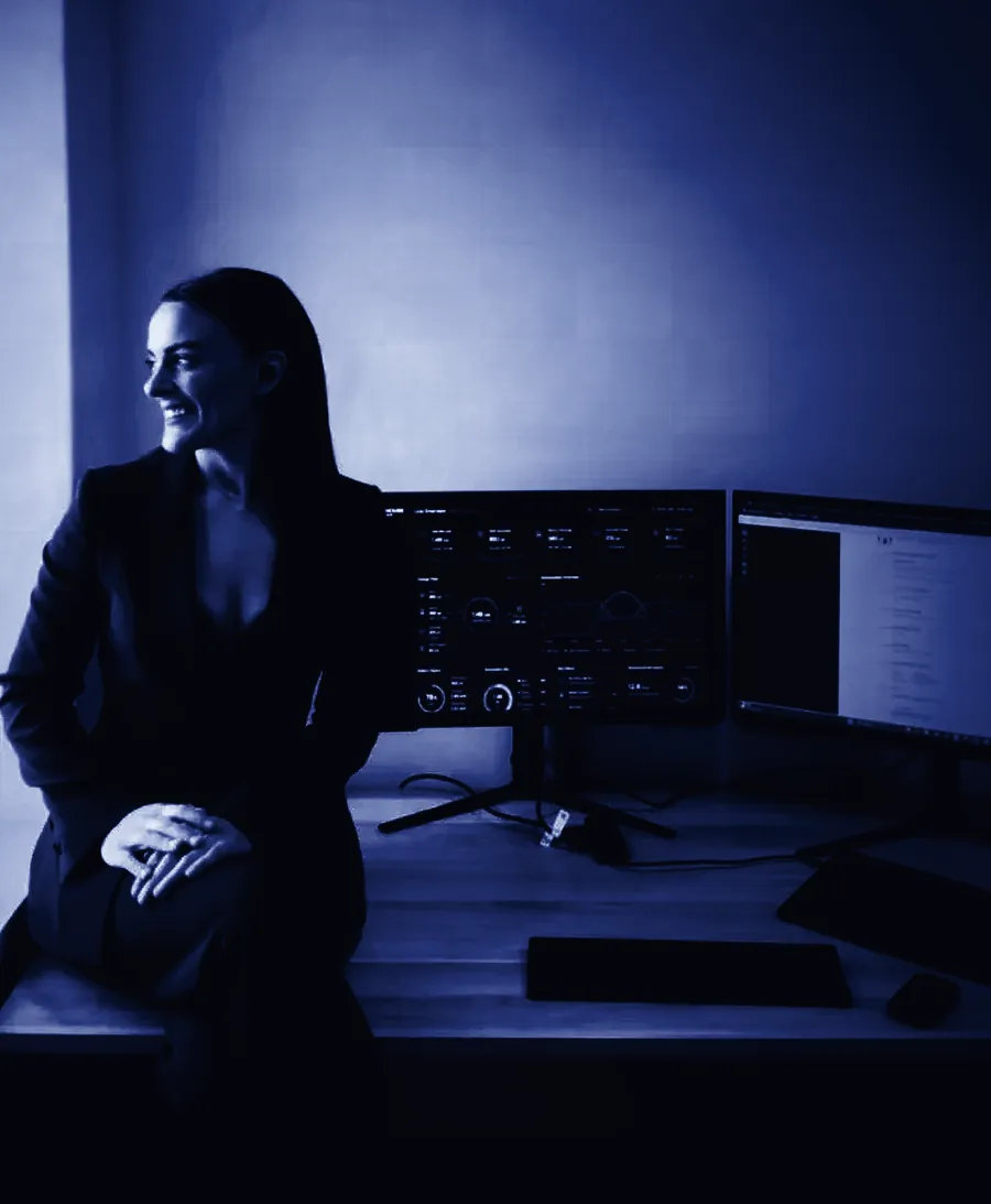 Brigette McDowell sitting on her desk in front of two monitors